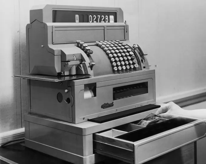 Close-up of a human hand taking money from cash register's drawer