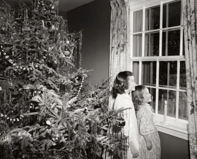 Side profile of two girls looking through a window