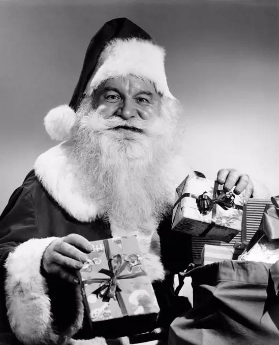 Portrait of Santa Claus holding Christmas presents and smiling