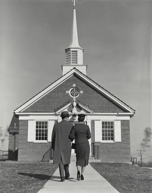 Vintage Photograph. Man and woman walking arm in arm toward small church