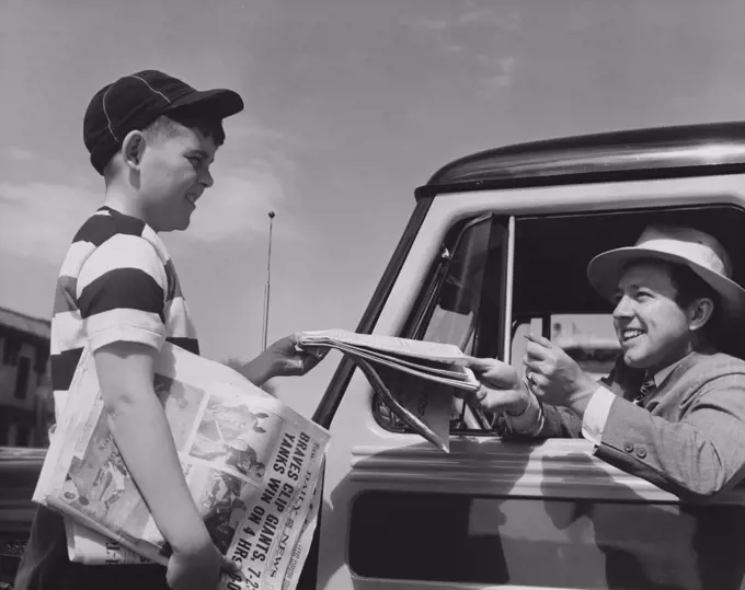 Young man buying a newspaper from a paper delivery boy