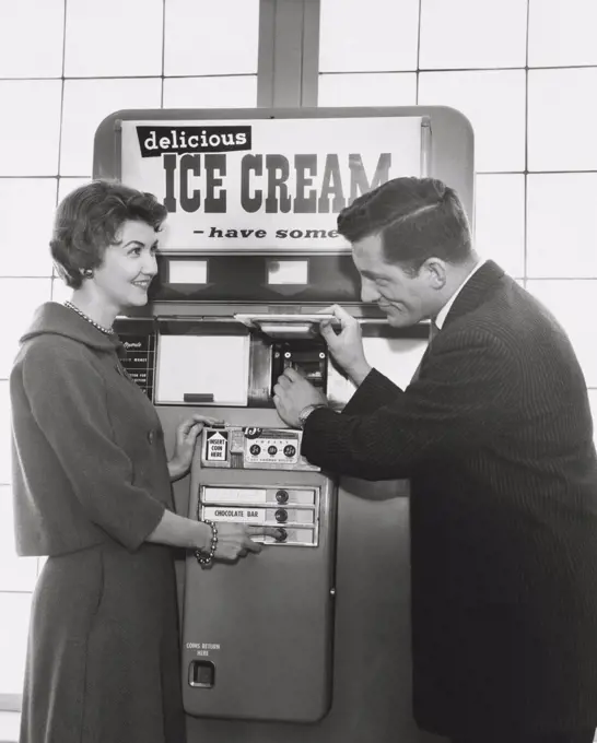 Mid adult couple purchasing ice cream from a vending machine