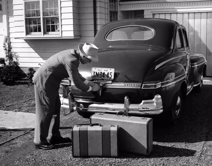 Man loading luggage into car trunk