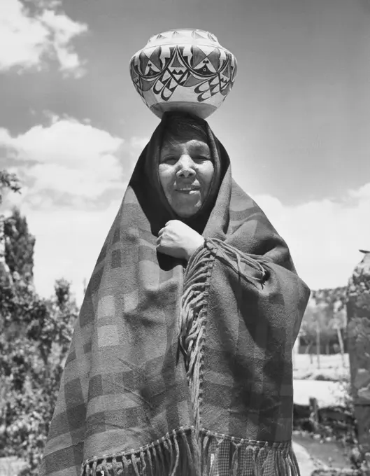 Jemez woman standing with a pottery on her head