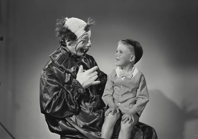 Vintage Photograph. Young boy sitting in lap looking up at clown