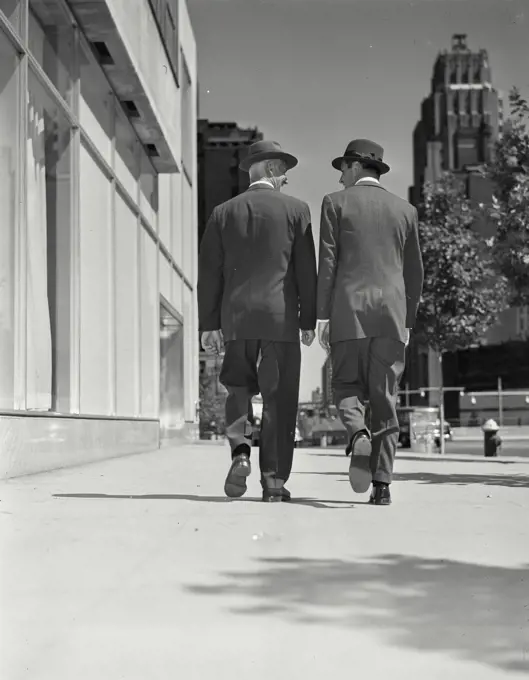 Bill Hammond, Bill Loock Models Released. Vintage Photograph. Two men wearing suits and hats walking outside on a city sidewalk away from camera