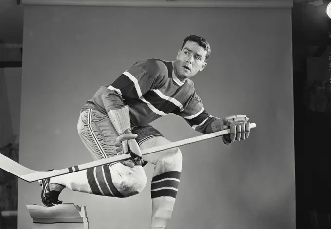 Vintage Photograph. Man in hockey uniform holding hockey stick ready to strike. Frame 3