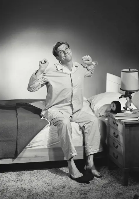 Vintage Photograph. Man in pajamas stretching after waking up. Frame 2