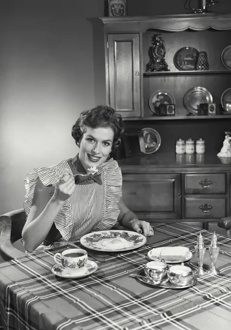 Vintage Photograph. Woman sitting at table and eating breakfast. Frame 1
