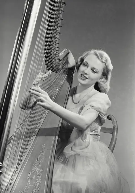 Vintage Photograph. Woman in dress sitting and playing Grand Pedal Harp. Frame 8