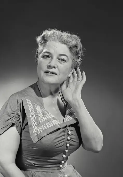 Vintage Photograph. Older woman in button blouse on empty background.