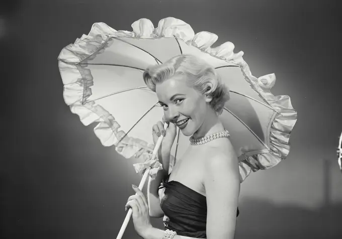 Vintage Photograph. Woman in dress holding umbrella over herself. Frame 2