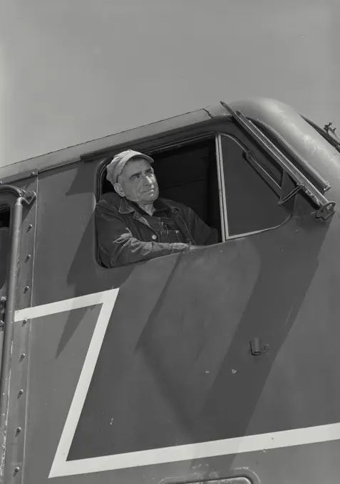 Vintage Photograph. Closeup of railroad engineer looking out of locomotive cab window with serious expression