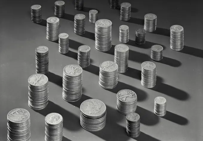 Vintage Photograph. Stacks of various American currency coins with shadows on solid surface, Frame 1