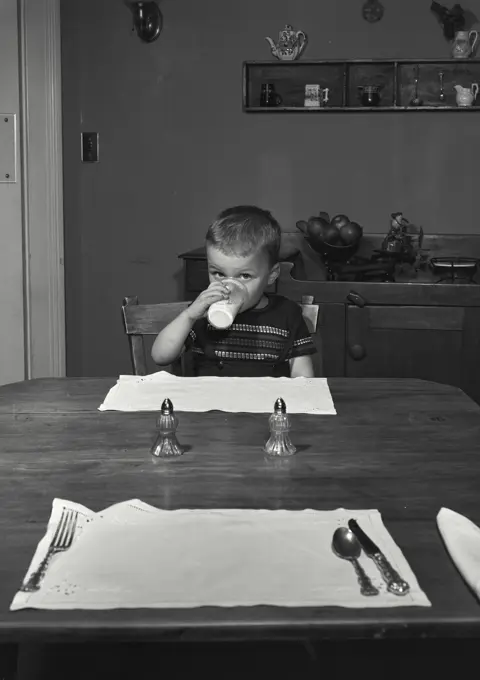 Vintage Photograph. Little boy drinking glass of milk.