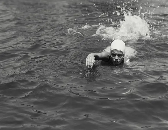 Vintage Photograph. Young lady wearing swim cap swimming in water outside