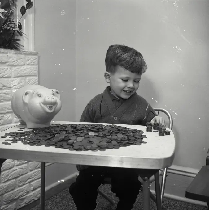 Vintage Photograph. Boy putting coins in piggy bank. Frame 2