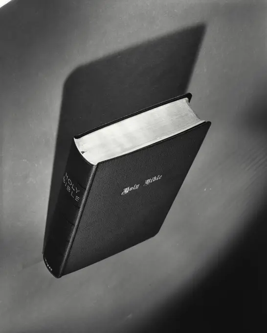 Vintage Photograph. Holy Bible sitting on surface with dramatic shadow and angle