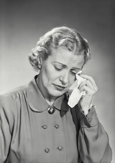 Vintage photograph. Woman in button coat wiping tears with handkerchief