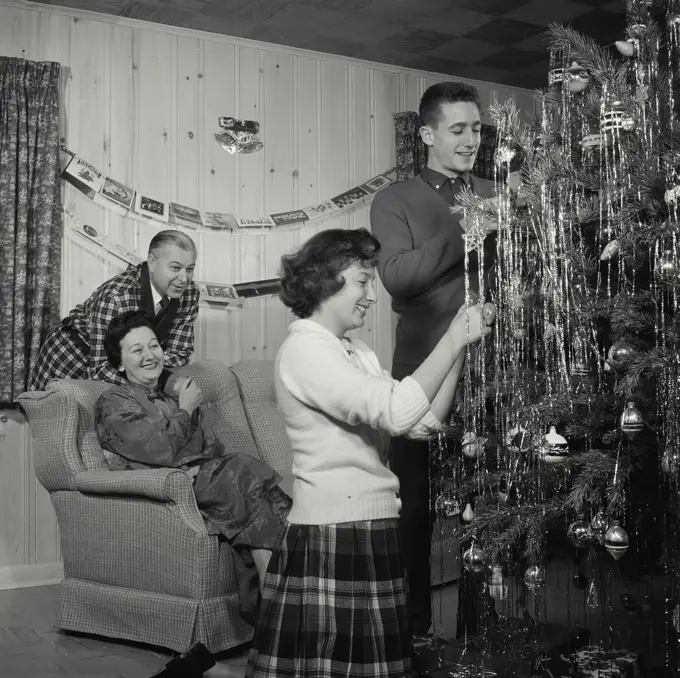 Vintage Photograph. Family Decorates Christmas tree together.