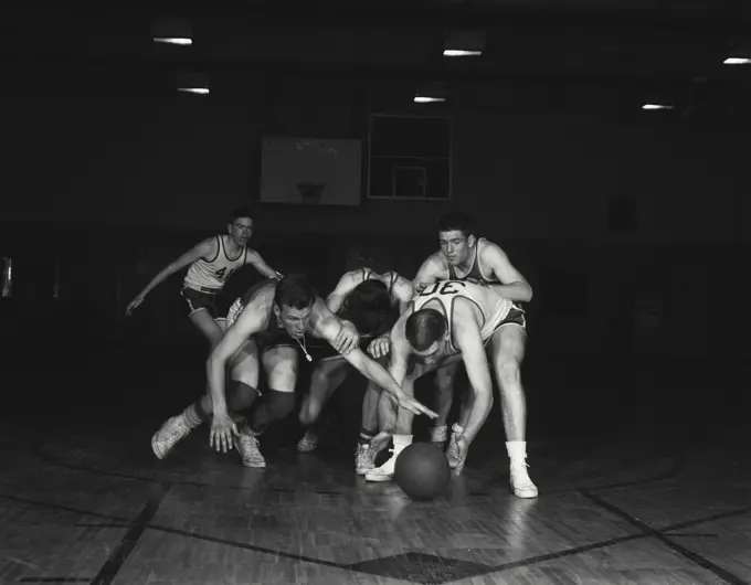 Vintage Photograph. Basketball players fight for ball on floor.