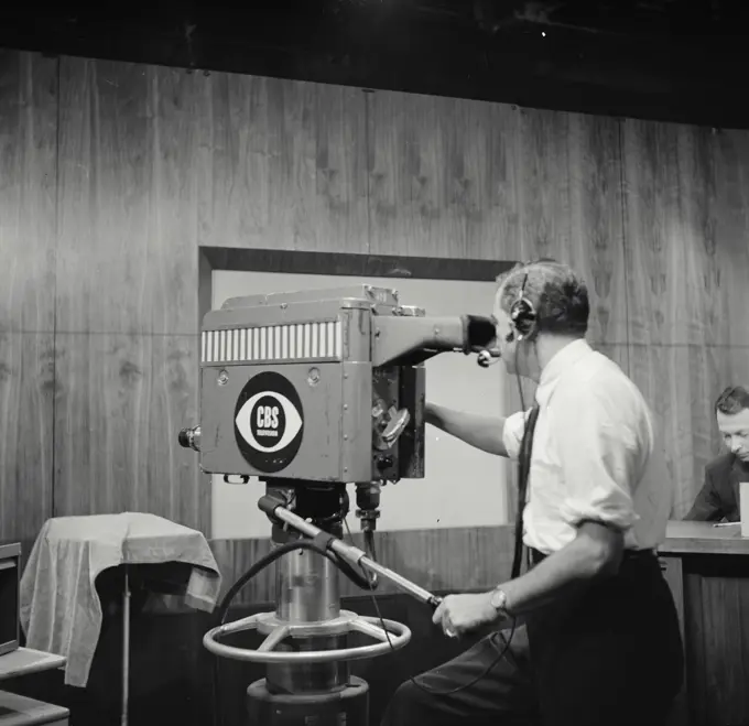 Vintage Photograph. Man operates CBS Television camera in studio from rear view.