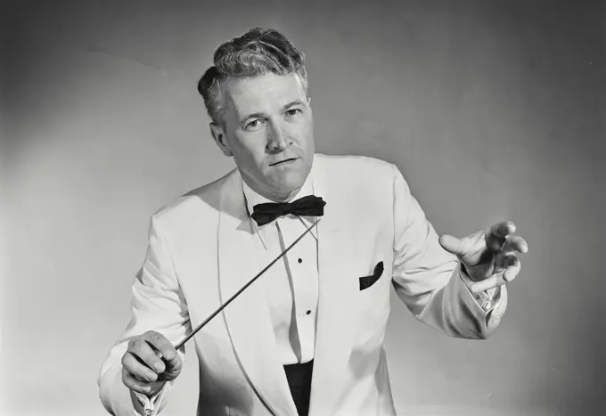 Vintage Photograph. Man directs band wearing white tuxedo.