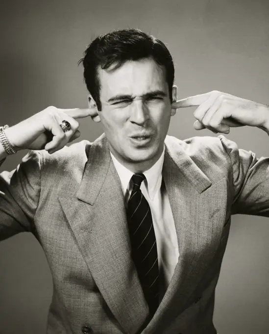 Close-up of a businessman closing his ears with his fingers