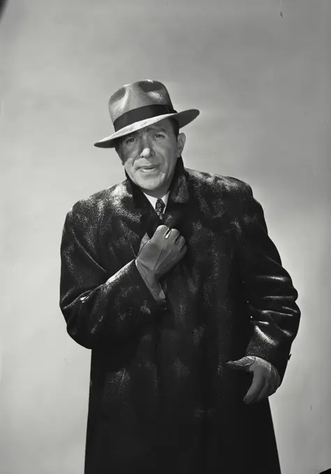 Vintage Photograph. Smiling man wearing hat and winter coat dusted with snow holding collar together looking cold