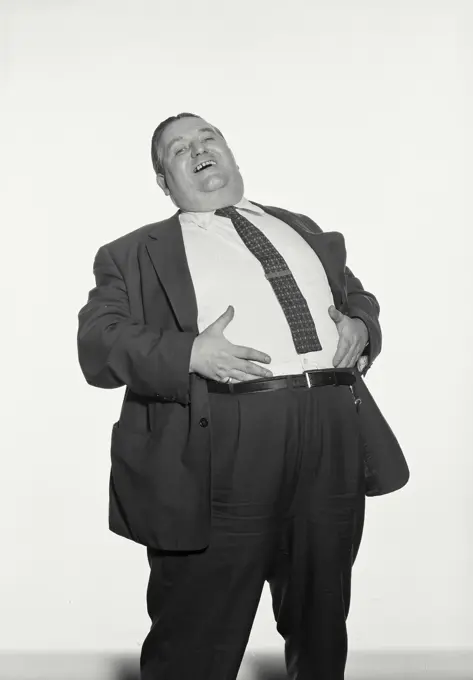 Vintage Photograph. Fat man wearing suit and tie laughing with hands on stomach