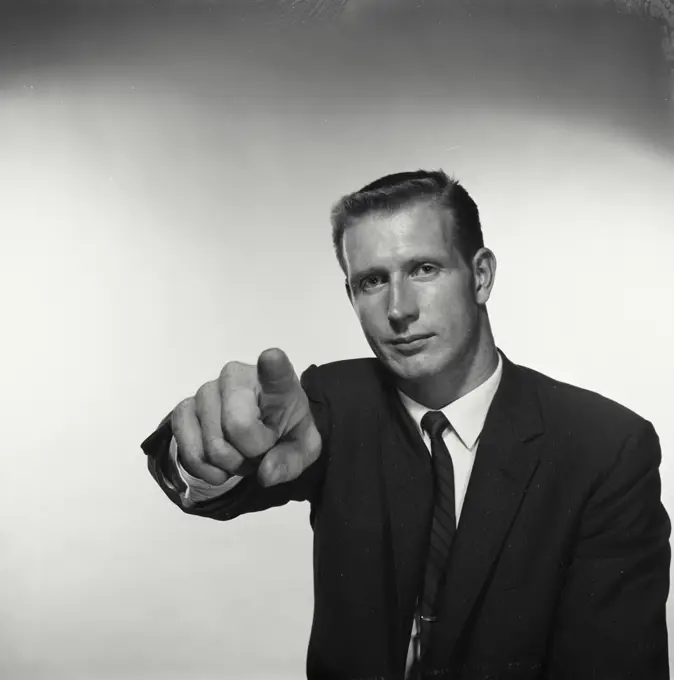 Vintage Photograph. Man points at camera in studio portrait.