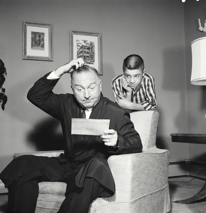 Vintage Photograph. Father scratches his head as he looks at childs report card who stands behind him.