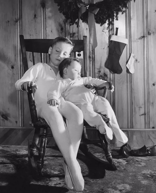 Two boys sleeping in a rocking chair