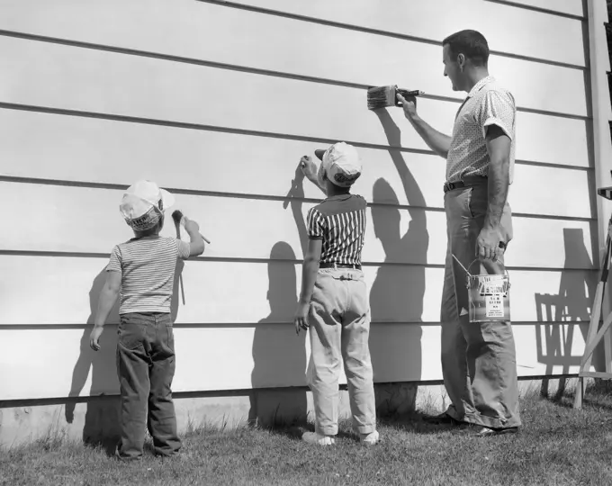 Side profile of a mature man with his two sons painting a wall