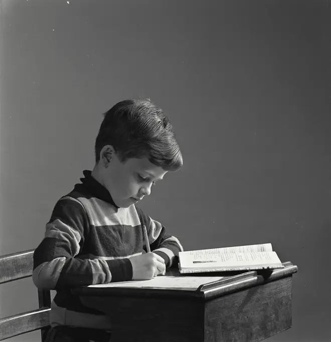 Vintage Photograph. Young boy at desk doing school work. Frame 1