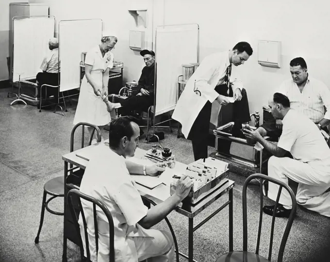 Vintage photograph. Doctors and a female nurse with patients in a hospital