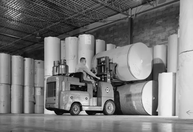 Rear view of a man driving a forklift in a warehouse