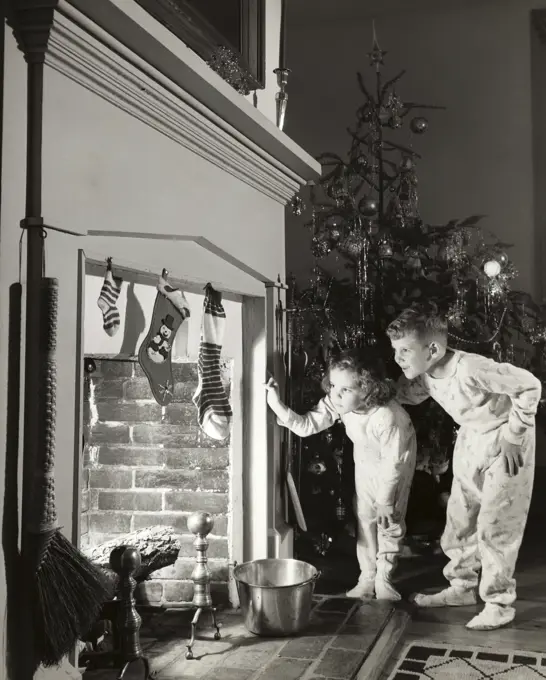 Boy and his sister peeking into a fireplace