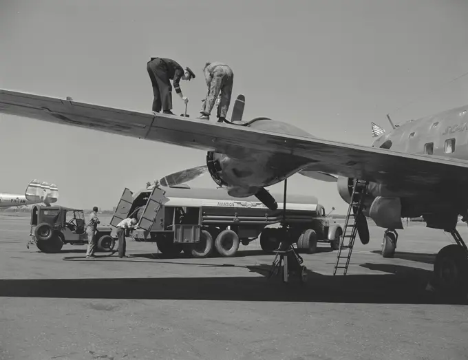 Vintage photograph. Member of flight crew gives final meter check to fueling of wing tanks on DC4 overseas airliner of the Scandinavian Airlines system