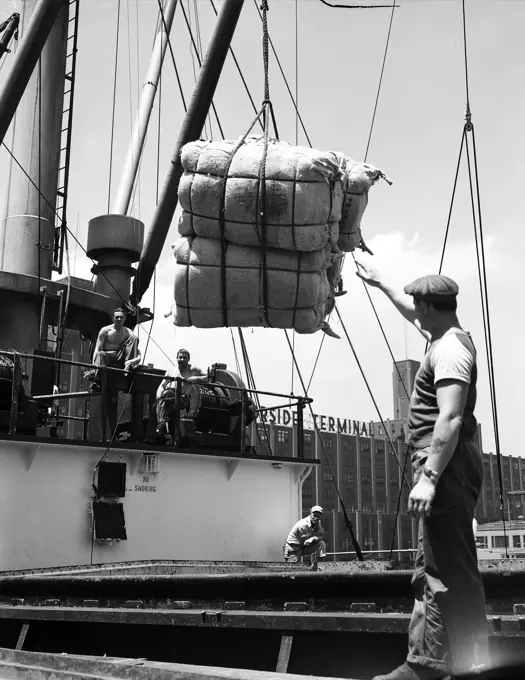 Dock workers unloading sacks from an industrial ship