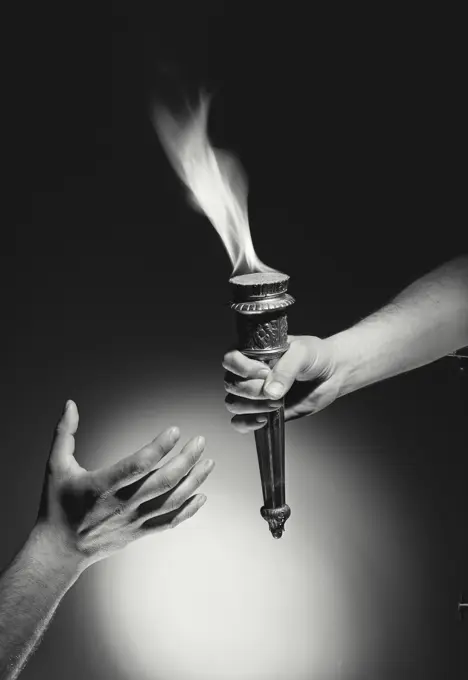 Vintage Photograph. Hand passing torch with flame to hand reaching up from bottom of frame with dark background, Frame 4
