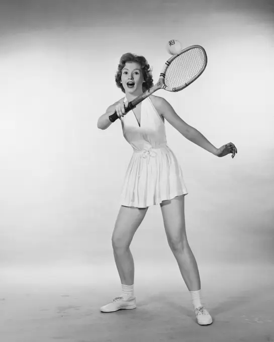 Young woman hitting a tennis ball with a tennis racket