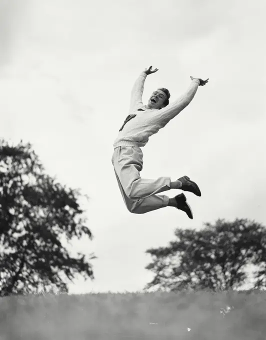 Vintage photograph. Man jumping in the air while pushing arms and legs back