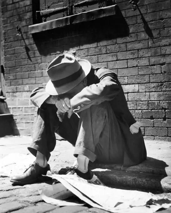 Homeless man sitting on a sidewalk