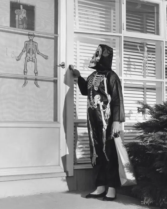 Person wearing a Halloween costume pressing the doorbell of a house