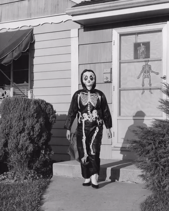 Person wearing a Halloween costume walking on a footpath outside a house