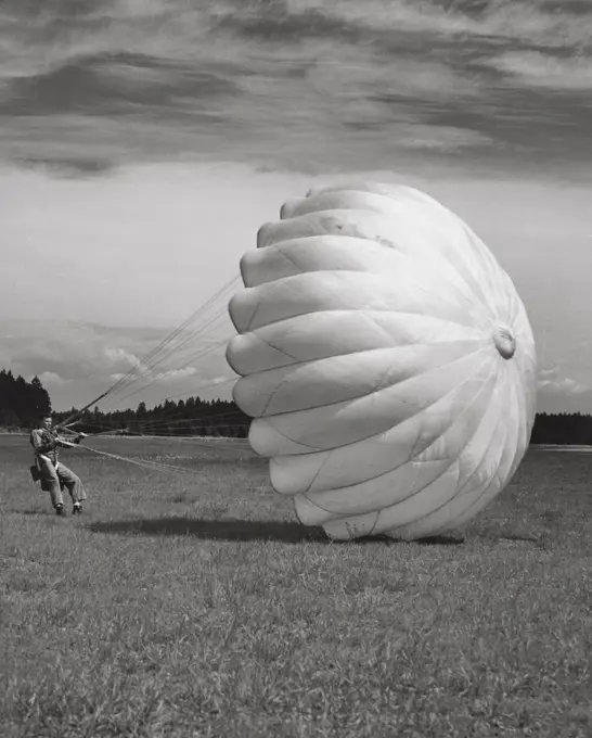 Man with a parachute landing in a field