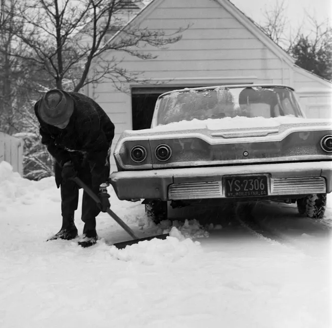 Man cleaning snow around car