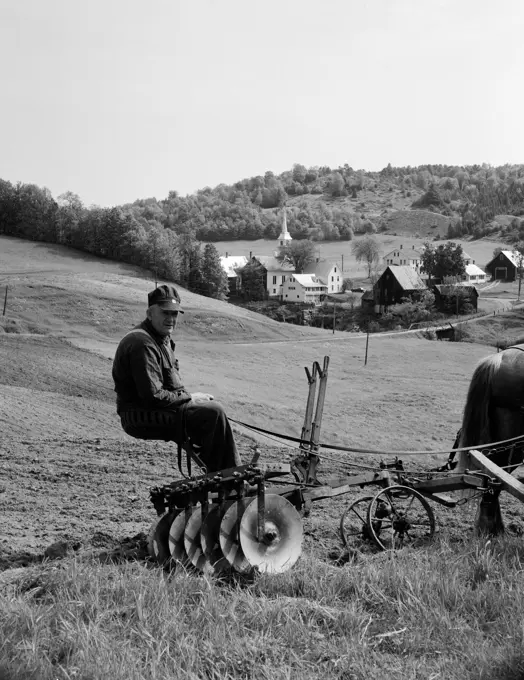 USA, Vermont, Corinth, farmer sitting on agriculture machine pulling by horse