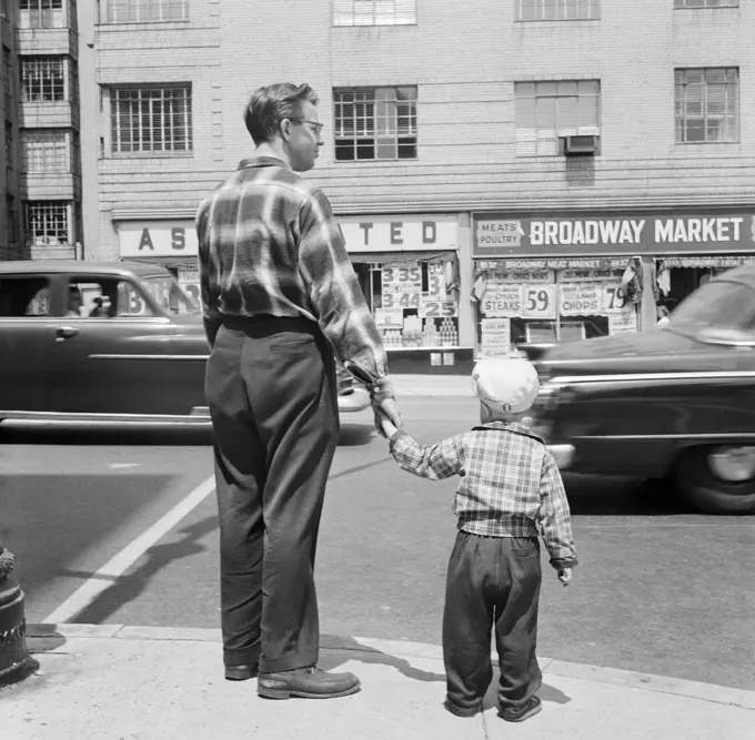 Father with son waiting at pavement to cross road